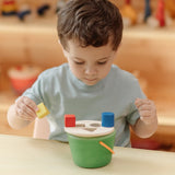 Child placing the coloured wooden blocks on top of the PlanToys geo sorting bucket wooden shape sorting toy. 