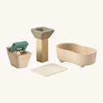 A close up view of the PlanToys wooden toilet with the seat up, sink bath and rug that go with the bathroom set