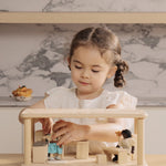 A child playing the PlanToys wooden space kitchen and dining set. Features a toy sink worktop, table, chairs, lamp and a cooking worktop.