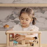 A child playing the PlanToys wooden space kitchen and dining set. Features a toy sink worktop, table, chairs, lamp and a cooking worktop.