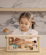 A child playing the PlanToys wooden space kitchen and dining set. Features a toy sink worktop, table, chairs, lamp and a cooking worktop.