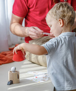 A child placing red red rocket top on the PlanToys Spatial Rocket. 
