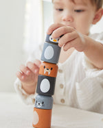 Close up of young boy making a tower with the PlanToys arctic animals matching figures on a white table.