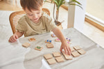 A young boy sat at a white marble table playing with the PlanToys wooden animal memory game. 