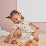 Girl leaning over to place a toy egg on top of the PlanToys stacking wooden bowls