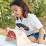 Child playing with the PlanToys Driving Console wooden toy, looking at one of the wing mirrors.
