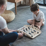 A child and adult playing with the PlanToys wooden soccer game. 