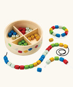 PlanToys threading beads wooden lacing toy. Rainbow coloured wooden beads with black and white laces in a handy wooden storage box with compartments.