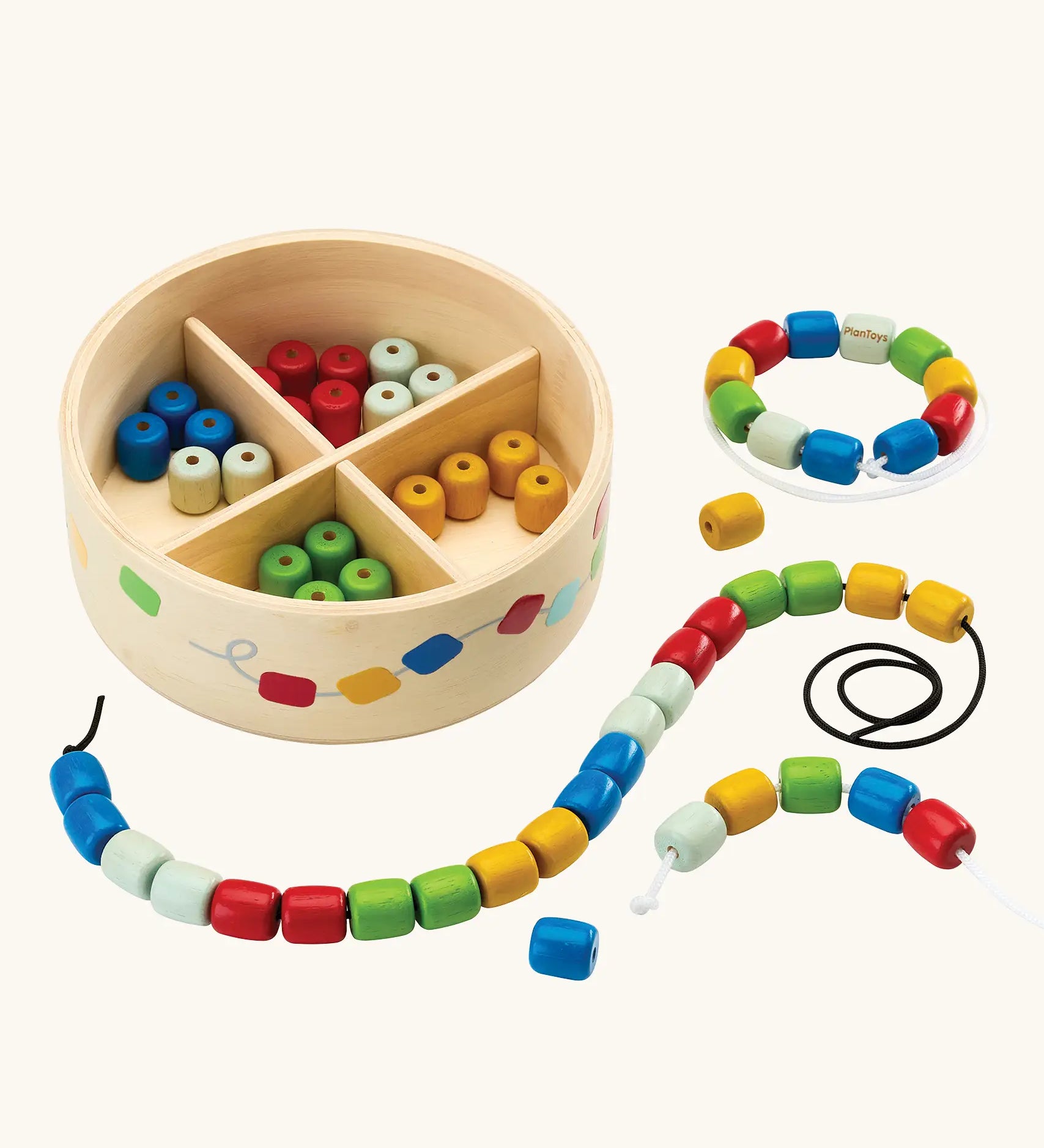 PlanToys threading beads wooden lacing toy. Rainbow coloured wooden beads with black and white laces in a handy wooden storage box with compartments.