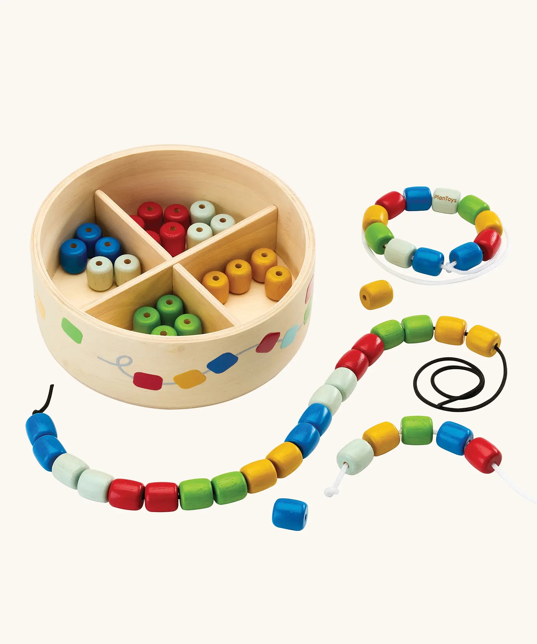 PlanToys threading beads wooden lacing toy. Rainbow coloured wooden beads with black and white laces in a handy wooden storage box with compartments.