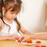 Child playing with PlanToys Travel Tic-Tac-Toe wooden game set. Cotton storage bag printed with a grid with 5 yellow x pieces and 5 red o pieces.  