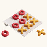 PlanToys Travel Tic-Tac-Toe wooden game set. Cotton storage bag printed with a grid with 5 yellow x pieces and 5 red o pieces.  