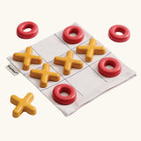 PlanToys Travel Tic-Tac-Toe wooden game set. Cotton storage bag printed with a grid with 5 yellow x pieces and 5 red o pieces.  