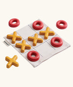 PlanToys Travel Tic-Tac-Toe wooden game set. Cotton storage bag printed with a grid with 5 yellow x pieces and 5 red o pieces.  
