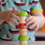 A child stacking three PlanToys Mushroom Kaleidoscopes on top of each other. 