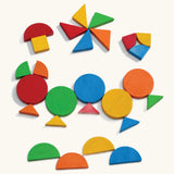 Girl arranging colourful mosaic shapes at a table near a dolls' house