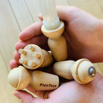The four tools from the PlanToys Touch & Guess Sensory Game being held in a person's hands. 
