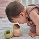 Close up of the PlanToys wooden sensory ball in a toddler's hand showing the fluffy texture inside
