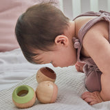 Close up of the PlanToys wooden sensory ball in a toddler's hand showing the fluffy texture inside