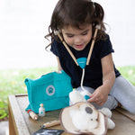 A child playing with the Plan Toys Play Vet Set, they have a teddy as their patient. 