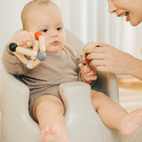 A baby playing with the PlanToys high contrast Triangle baby Clutching Toy. A black and natural wood wooden ball in a stretchy triangle clutching toy. PlanToys range of toys are made from sustainably sourced rubberwood, we're proud stockists of PlanToys here at Babipur. 