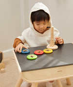 A child sitting at a table playing with the PlanToys Twist & Sort toy.