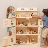 Children playing with the PlanToys Grand Victorian Dollhouse. Front and roof shown open and all floors and attic room has PlanToys dolls house furniture inside.