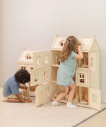 Children playing with the PlanToys Grand Victorian Dollhouse. The smaller Victorian dolls house is next to it.