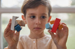 Close up of a child holding pieces of the PlanToys kids slotting block toy puzzle. 