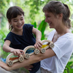 A child playing with the PlanToys Water Block Cars, the child is placing them on an adult's arm. 
