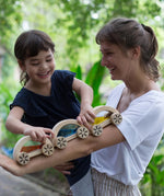 A child playing with the PlanToys Water Block Cars, the child is placing them on an adult's arm. 
