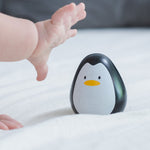 A baby's hand reaching for the PlanToys wobbly wooden penguin toy. 