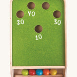 An overhead view of the PlanToys Ball Shoot Board Game on a plain background. Chalk has been used to write score numbers near the holes. 