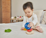 A baby playing with the Plan Toys Wave Stacker - a wooden stacking rainbow baby toy.