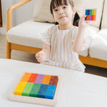 A child playing with the PlanToys 100 Rainbow Counting Cubes. The child is holding up one of the idea cards and has created the same pattern with the cubes. 