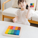 A child playing with the PlanToys 100 Rainbow Counting Cubes. The child is holding up one of the idea cards and has created the same pattern with the cubes. 
