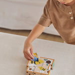 A child playing with the PlanToys Wooden Animal Puzzle Cubes, they are placing the blocks to form the bee themed photo. 
