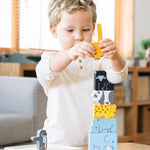 A child stacking the pieces from the Plan Toys Animal Puzzle Game
on the wooden base that comes with the game.