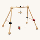 PlanToys High Contrast Wooden Baby Play Gym. A wooden baby gym with high contrast coloured features and detailing. The gym comes with two wooden hanging toys, a planet and a rocket. PlanToys range of toys are made from sustainably sourced rubberwood, we're proud stockists of PlanToys here at Babipur. 