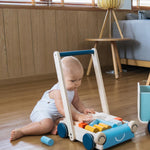 Young baby playing with wooden toy blocks in the Plan Toys orchard baby walker
