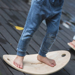 A close up of a child's feet on the PlanToys Balance Board.

