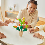 Three adults sitting around a table playing with the  PlanToys Balancing Cactus.
