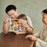 Close up of hands grabbing pieces of the PlanToys stacking wooden beaver tumble kids game