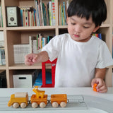 Child playing with the PlanToys yellow wooden cargo train on a rubber railway track set and small wooden animal figures. 