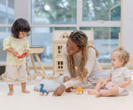 Two children and an adult playing with the PlanToys Dino wooden Car toys. A blue coloured diplodocus, a yellow stegosaurus and red coloured t-rex dinosaur figures on wheels. PlanToys range of toys are made from sustainably sourced rubberwood, we're proud stockists of PlanToys here at Babipur. 