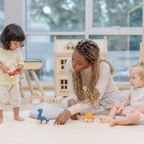 Two children and an adult playing with the PlanToys Dino wooden Car toys. A blue coloured diplodocus, a yellow stegosaurus and red coloured t-rex dinosaur figures on wheels. PlanToys range of toys are made from sustainably sourced rubberwood, we're proud stockists of PlanToys here at Babipur. 