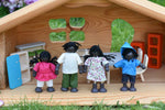 The PlanToys doll house family set placed in an Ostheimer dolls house. The dolls have black skin and black hair.