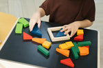 Close up of child's hands playing with the PlanToys solid wooden fraction blocks on a wooden table