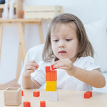 A child playing with the PlanToys Fractions Cubes. They are creating a stack. 