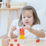 A child playing with the PlanToys Fractions Cubes. They are creating a stack. 